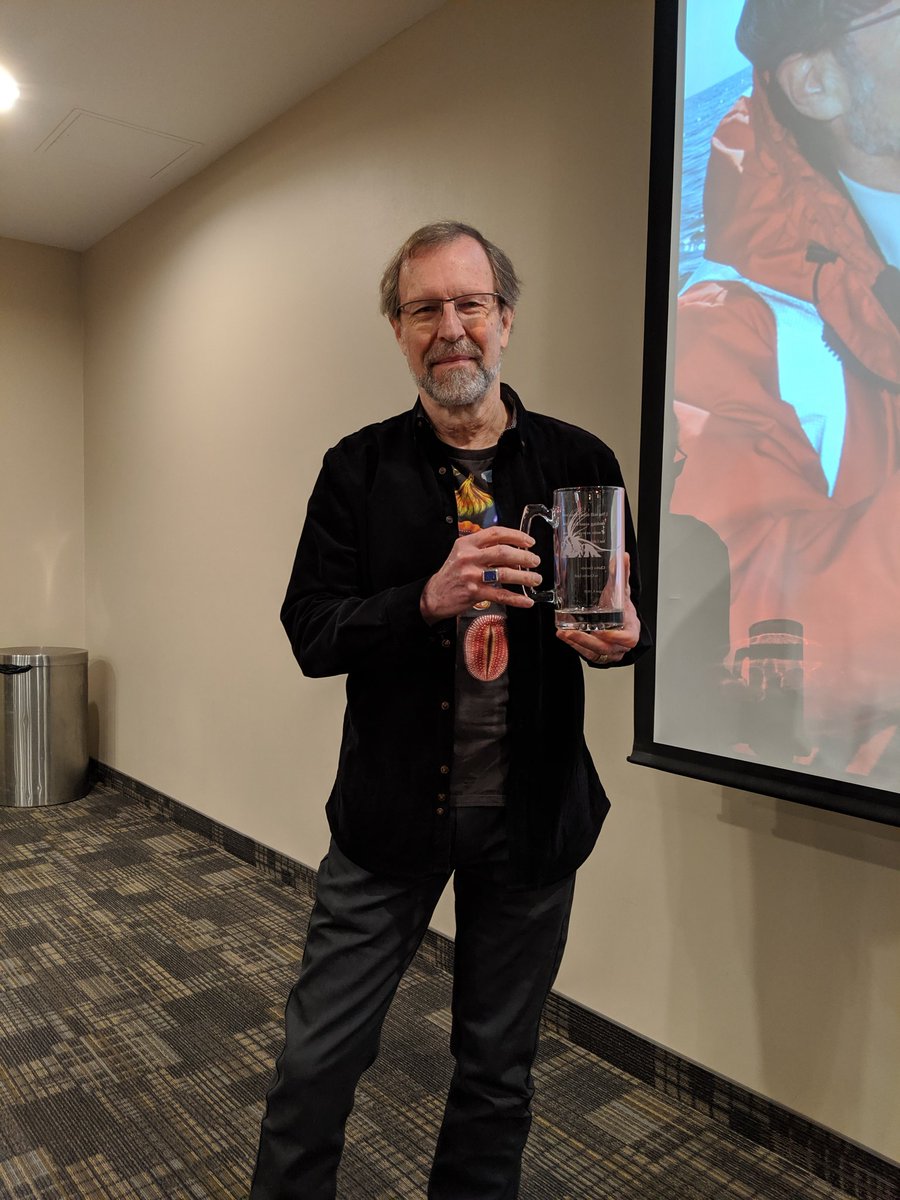 PalmerSymposium's tweet photo. Rich ended his closing remarks with the Ediacaran t-shirt. In his hands is his new personal beer mug, featuring barnacle appendages and a Darwin quote, a gift from the lab alumni. Embrace diversity. #cszscz2019 https://t.co/KXoiWegodj