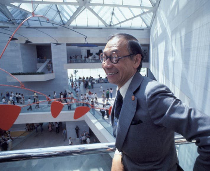 I.M. Pei smiling on the second floor overlooking an art museum atrium with a Calder mobile hanging nearby