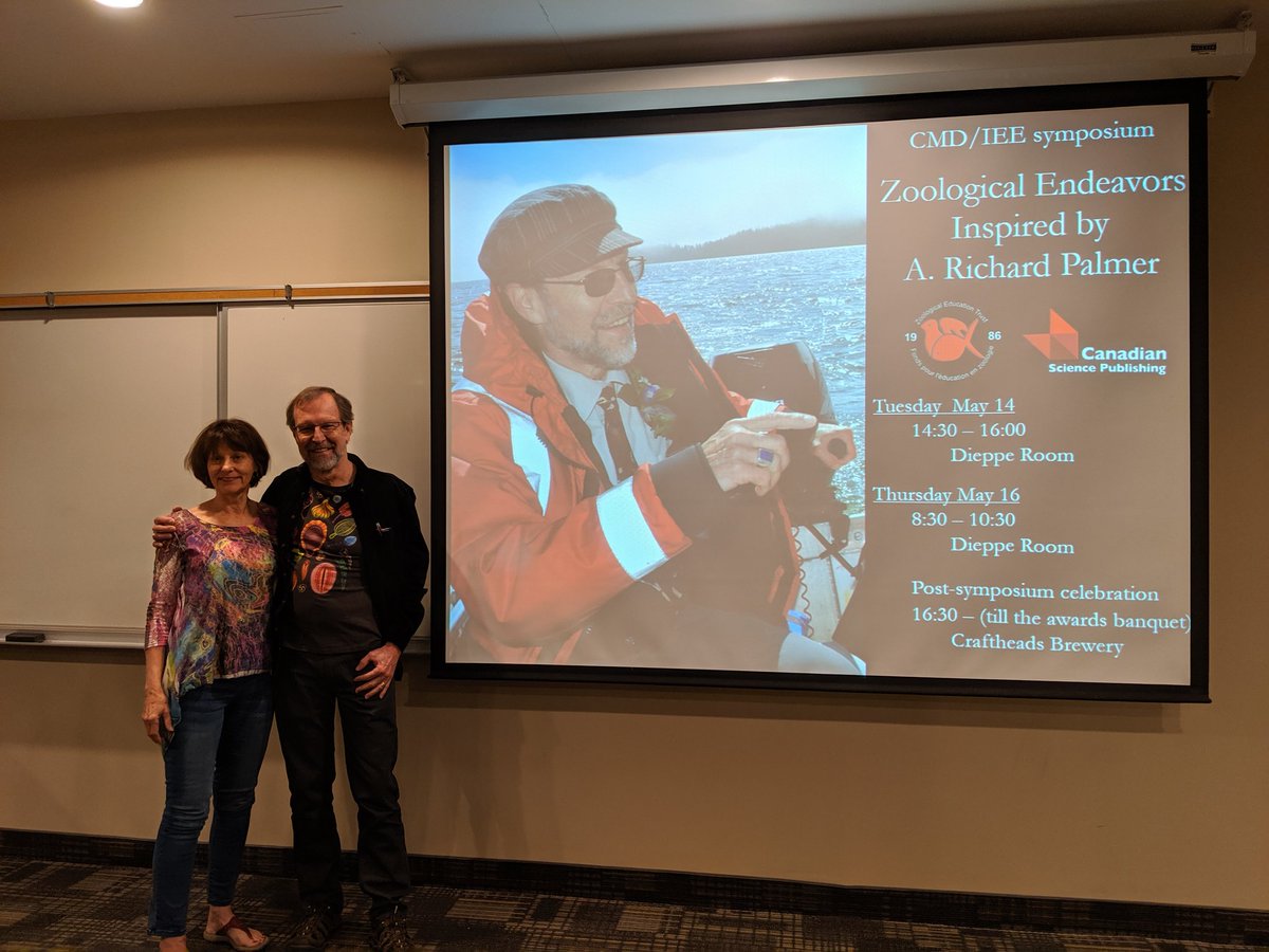 PalmerSymposium's tweet photo. Rich Palmer and Lois Hammond -- academic parents of the Palmer Lab alumni -- with the symposium graphics. https://t.co/6SlioCbikp