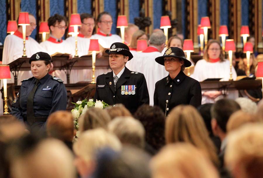 Three police women carry a wreath through Westminster Abbey