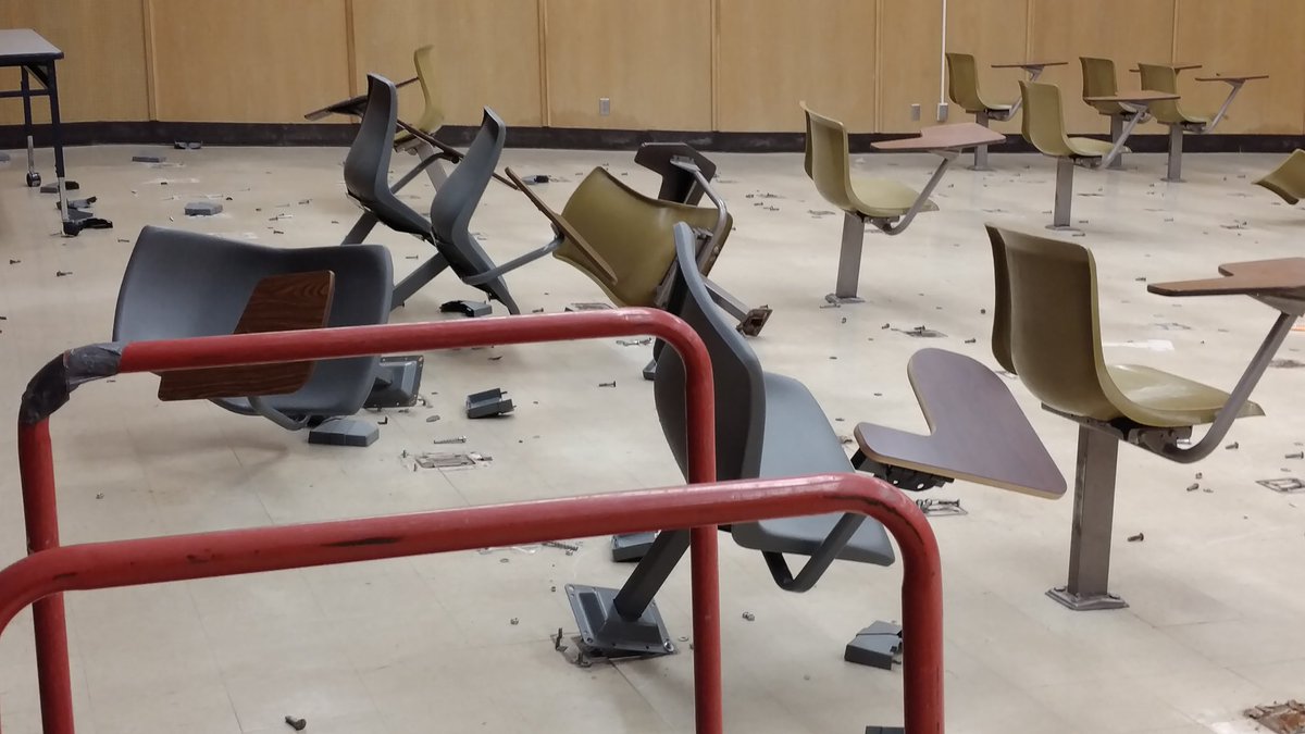 Some of the chairs remain fixed to the floor, while others are only partially removed from the floor and are leaning to one side or another