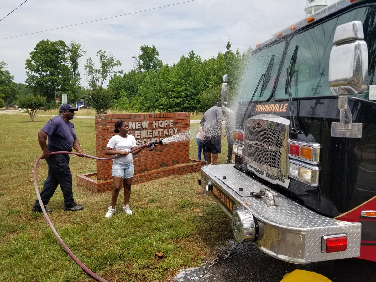 Fire Chief Daren Small gives Lakaiyah more firehose to spray off the front of the fire truck.