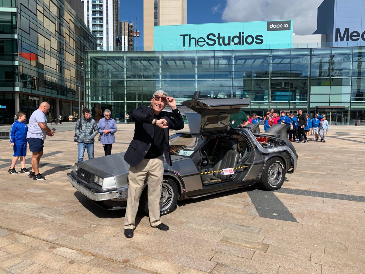 MediaCityUK's tweet photo. Hey Doc! The one and only time-traveling DeLorean from @BacktotheFuture  is right here on the Piazza with Writer, Bob Gale, to celebrate @BTTFmusical which will be premiering in Manchester February 2020!🎬⚡️ https://t.co/QoO9RXktrC