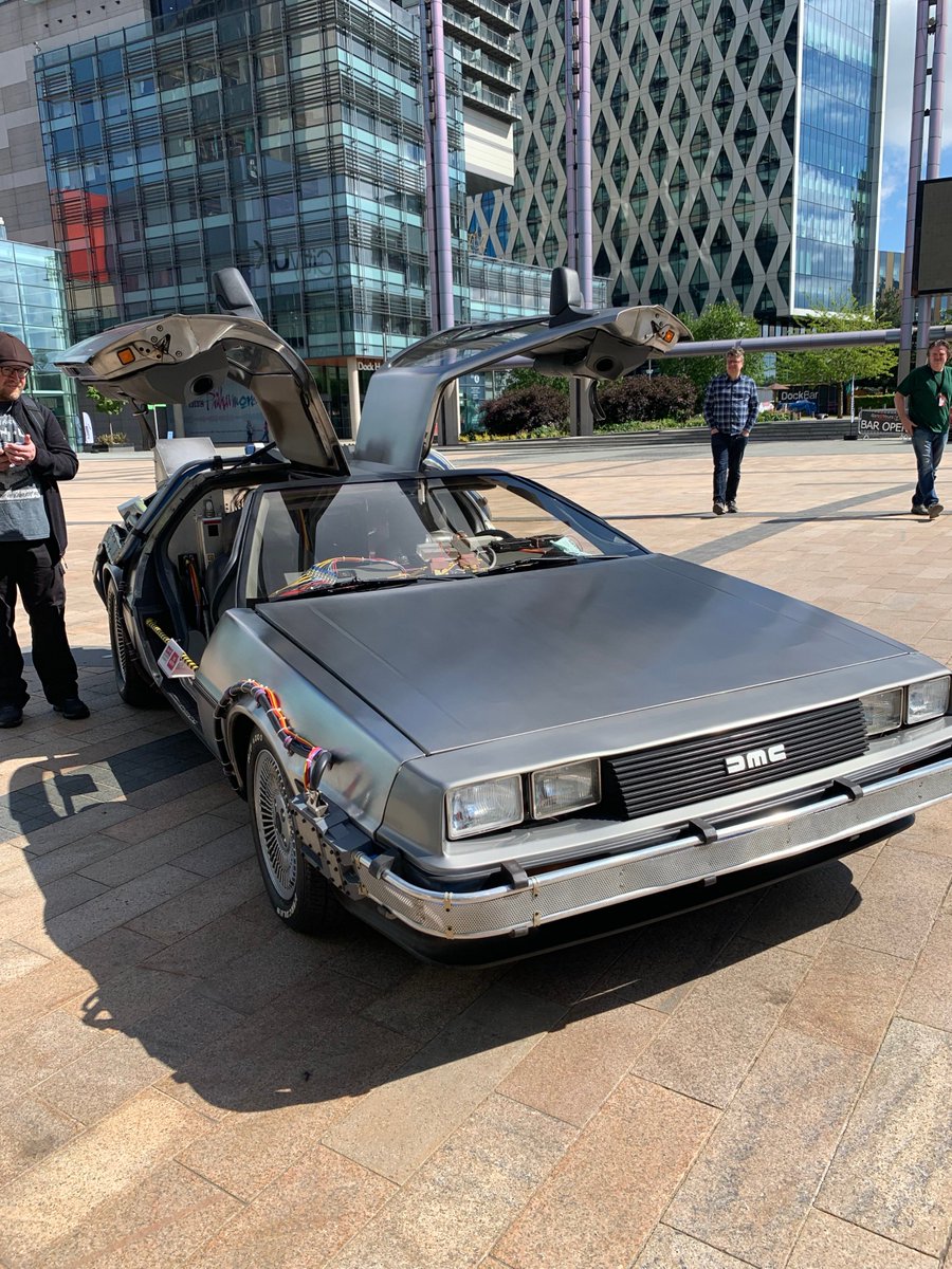 MediaCityUK's tweet photo. Hey Doc! The one and only time-traveling DeLorean from @BacktotheFuture  is right here on the Piazza with Writer, Bob Gale, to celebrate @BTTFmusical which will be premiering in Manchester February 2020!🎬⚡️ https://t.co/QoO9RXktrC