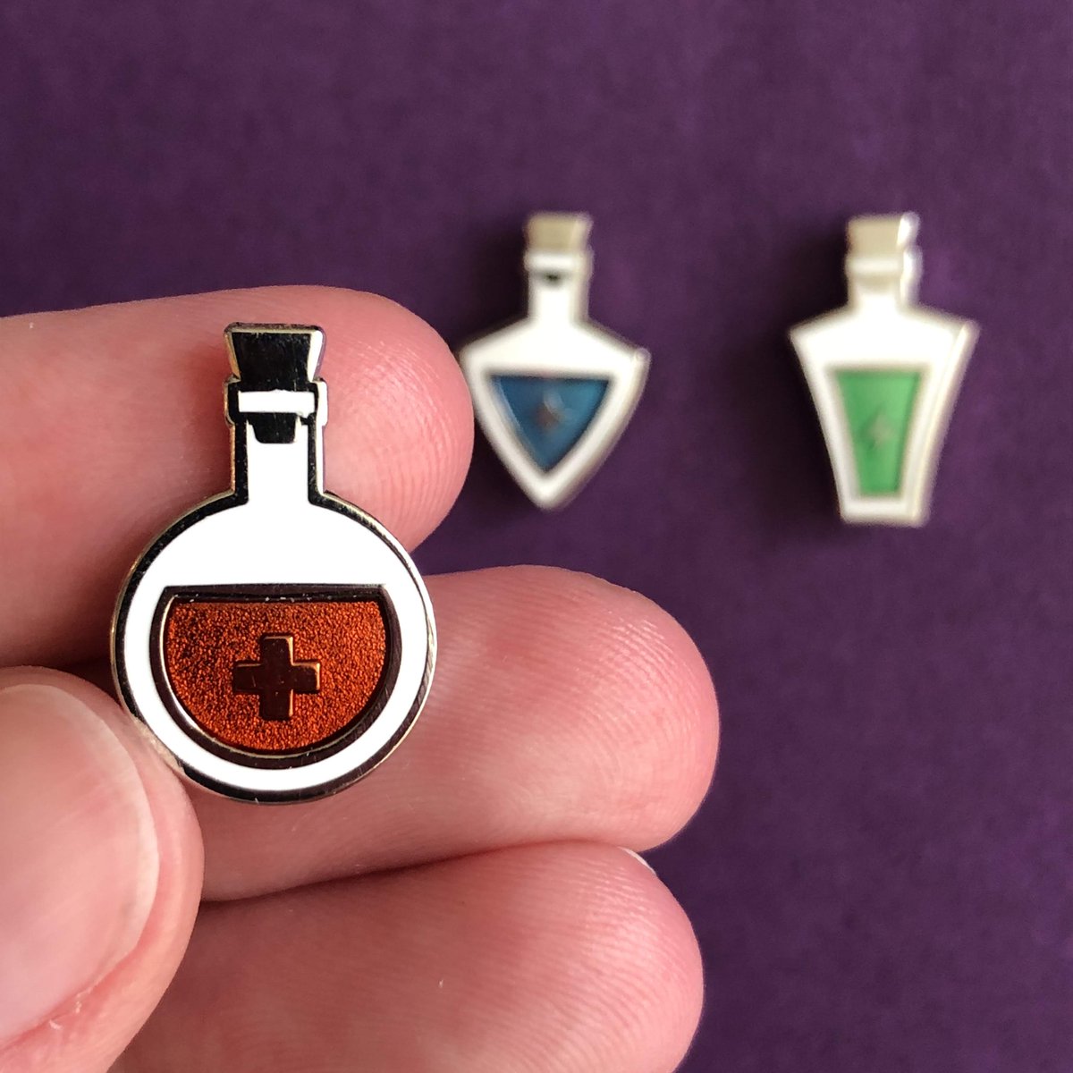 NEW STUFF has arrived in my shop! First up: a 3-pin set of health, mana, and stamina potions. This is my first time designing something with transparent enamel -- they turned out real cute. emilycheeseman.myshopify.com/products/healt…