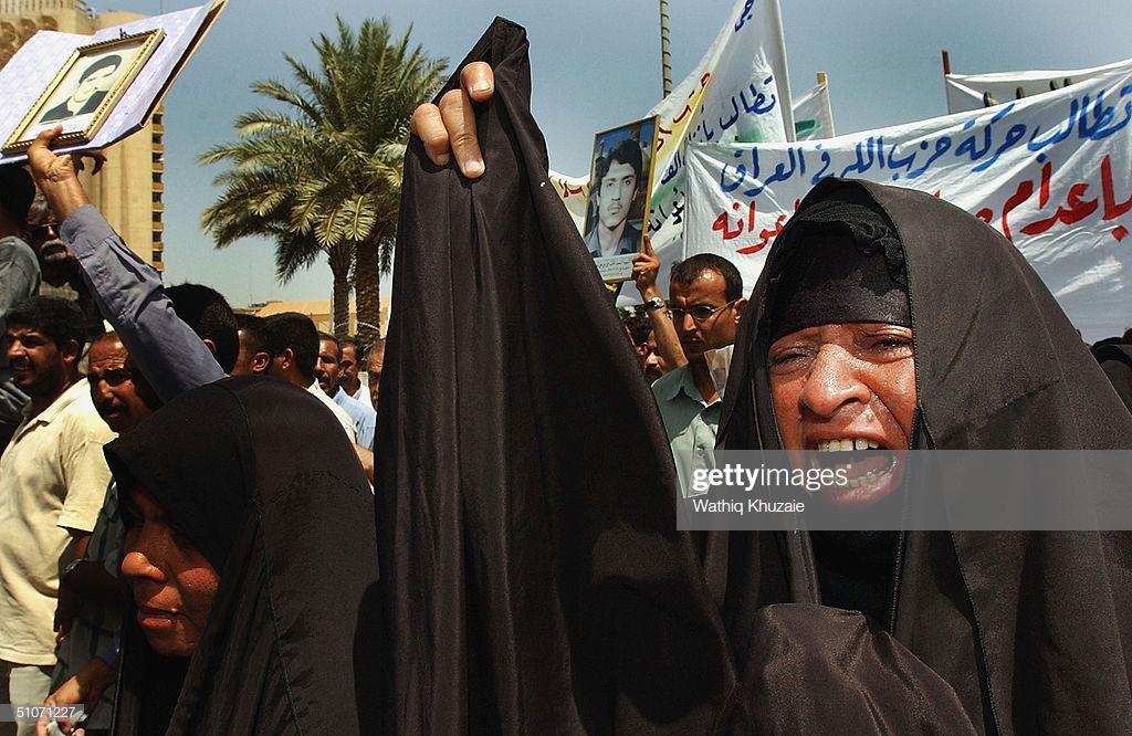 21 - Iraqis hold up pictures of murdered family members, demanding the execution of Saddam Hussein. (Baghdad Iraq, 2004)