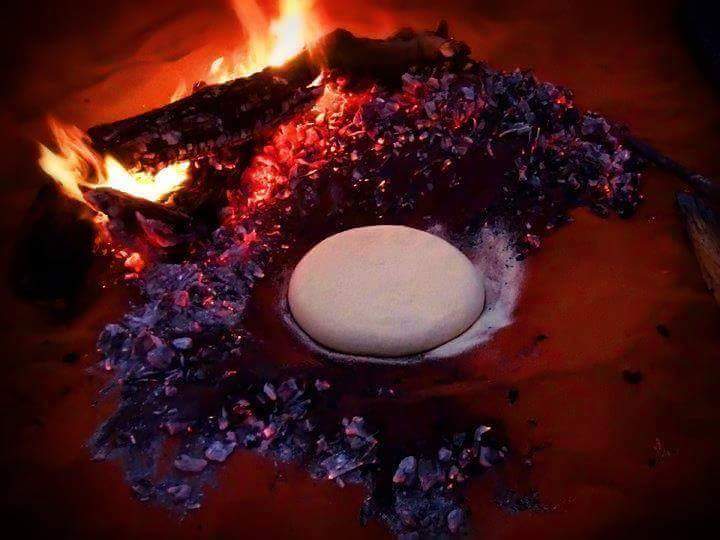TAGUELLAsignifie « nourriture noble » Ce pain Tuareg est une épaisse galette sans levain, longuement pétrie puis cuite sous les braises, la cendre et le sable qu'ensuite on trempe et fragmente dans une sauce à base de tomate et de légumes, parfumée au fenouil sauvage (tattayt).