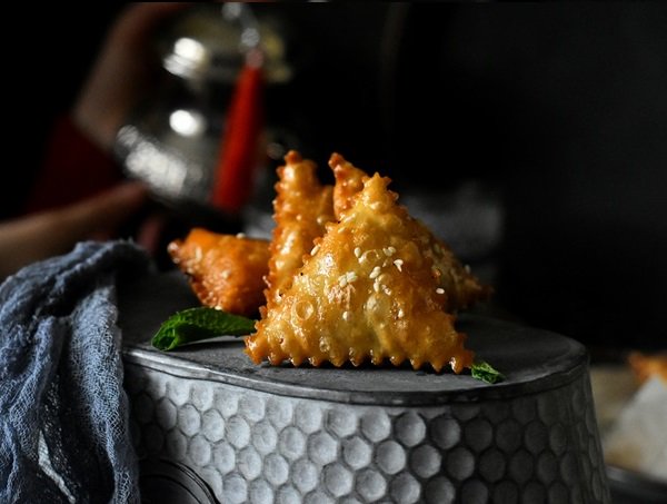 SAMSAUne pâtisserie de forme triangulaire aux amandes et au miel, préparée surtout pour l'Aïd el-Fitr. Après la friture, les samsa sont trempées dans un sirop à base de miel et d'eau de fleur d'oranger puis saupoudrées de graines de sésame.