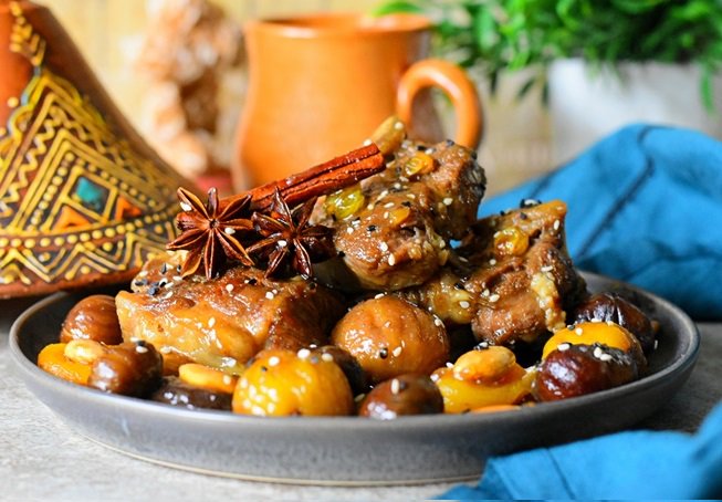 TAJINE BEL KASTELTajine d’agneau aux châtaignes ou marrons qui nous vient de la région de Tlemcen. Arroser de sauce et raisins secs et servir chaud et parsemer de graines de sésames si désiré. Ajoutez des pruneaux ainsi que des abricots séchés pour plus de saveur et de goût.