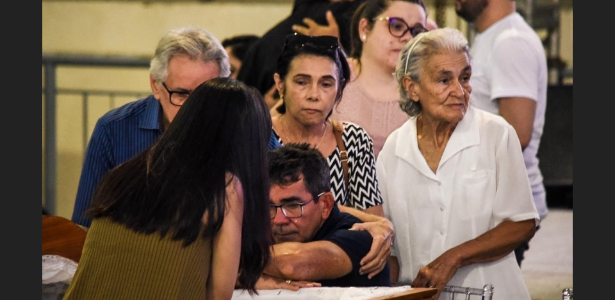 Corpo de Gabriel Diniz é velado em cerimônia aberta ao público em João Pessoa uol.page.link/dKBNr #PraCegoVer #PraTodosVerem Foto do pai de Gabriel Diniz chorando à beira do caixão do filho, no velório em João Pessoa. Outros familiares rodeiam o caixão