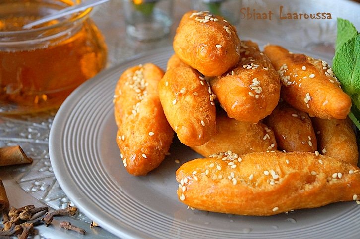 SBIAAT LAAROUSSADes beignets d'origine Algéroise qui signifie littéralement « les doigts de la mariée », de par sa forme qui ressemble à des doigts, mais aussi parce que, à l'époque, cette pâtisserie était le premier gâteau que devait confectionner la nouvelle mariée.