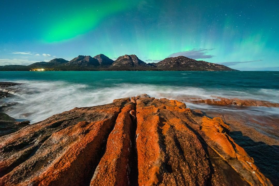When a dancing Aurora, the lichen-topped rocks of the Freycinet Peninsula and a full moon collide, this is what you get! 😮💚🌌 (Pic: instagram.com/beautyoftasman…) #seeaustralia #discovertasmania