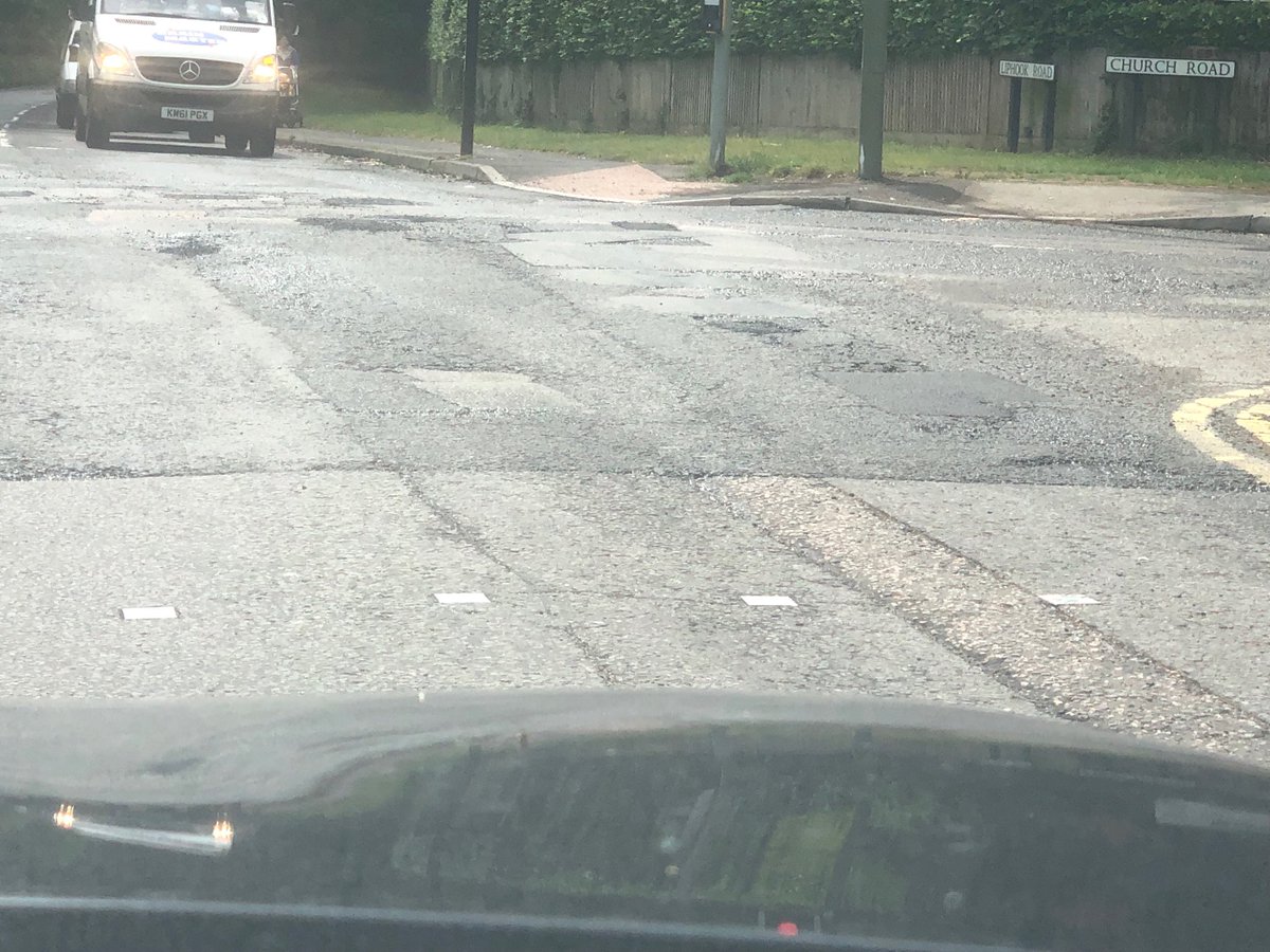 Petetinson's tweet photo. Surrey County Council’s idea of acceptable pothole repairs, a shovel,of rough tarmac in each hole and trodden down. #shakeyourfillingsout #roadacne https://t.co/Kdhvul6i4R