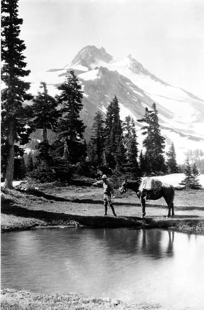 ForestServiceNW's tweet photo. An early ranger leads his horse on the old Santiam National Forest past a lake within the foothills of Mt. Jefferson back in 1931. #Throwback #History https://t.co/toWggys2cR