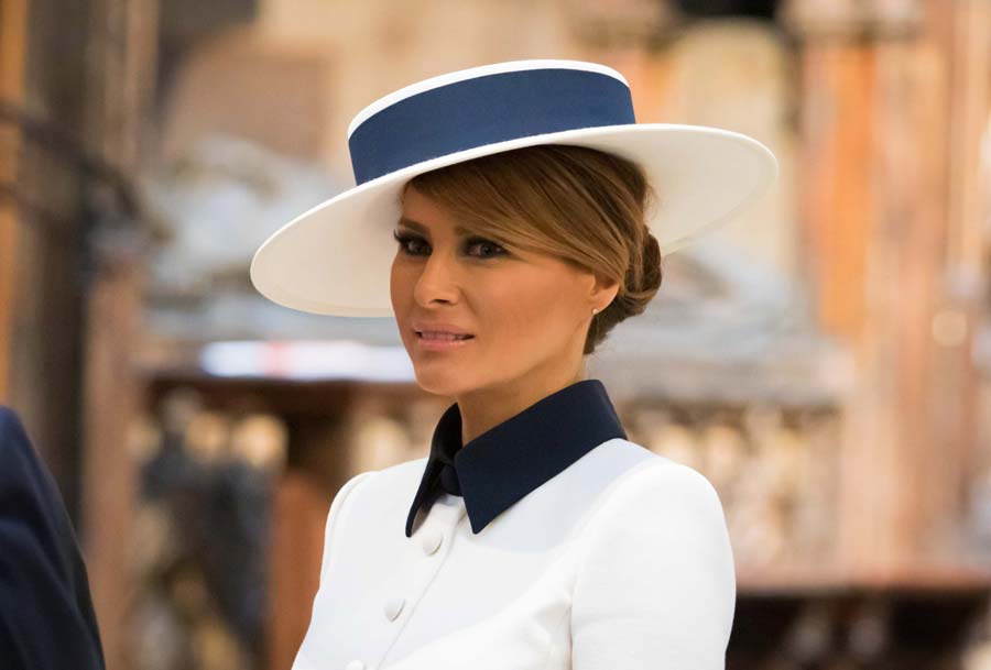 Melania Trump during her tour of the Abbey, she wears a white suit with a blue collar and a white hat with a blue band