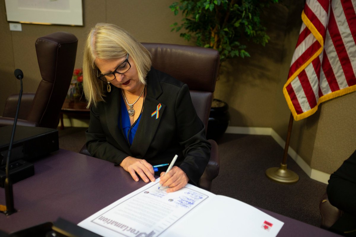 Commissioner Moore signing a proclamation, sitting at the dais inside the BCC Chambers. 