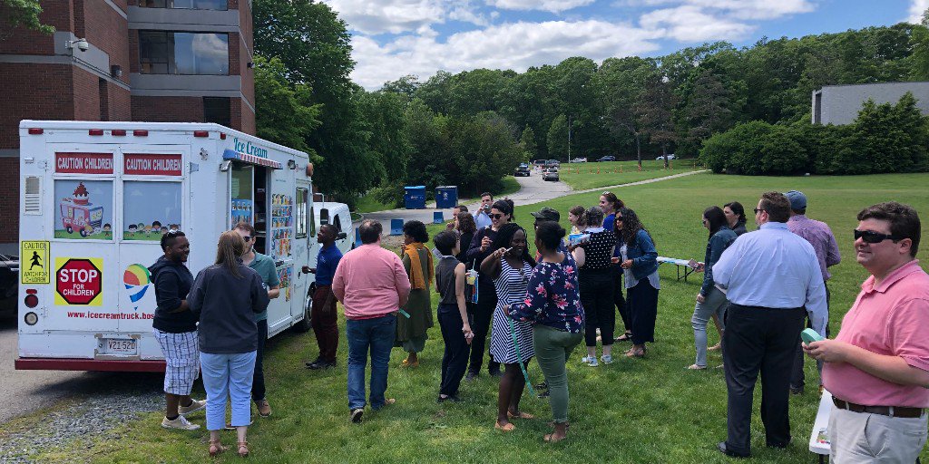 Brandeis Summer School students, faculty and staff enjoying ice cream while  talking and laughing outside on the Chapel's Field lawn.
