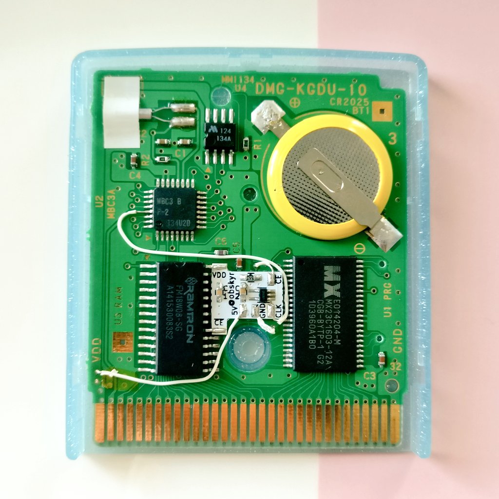 The innards of a Pokémon Crystal cartridge, with a mysterious but cute little white daughter board attached in the middle. That board is the FRAM Signal Sorcerer!
