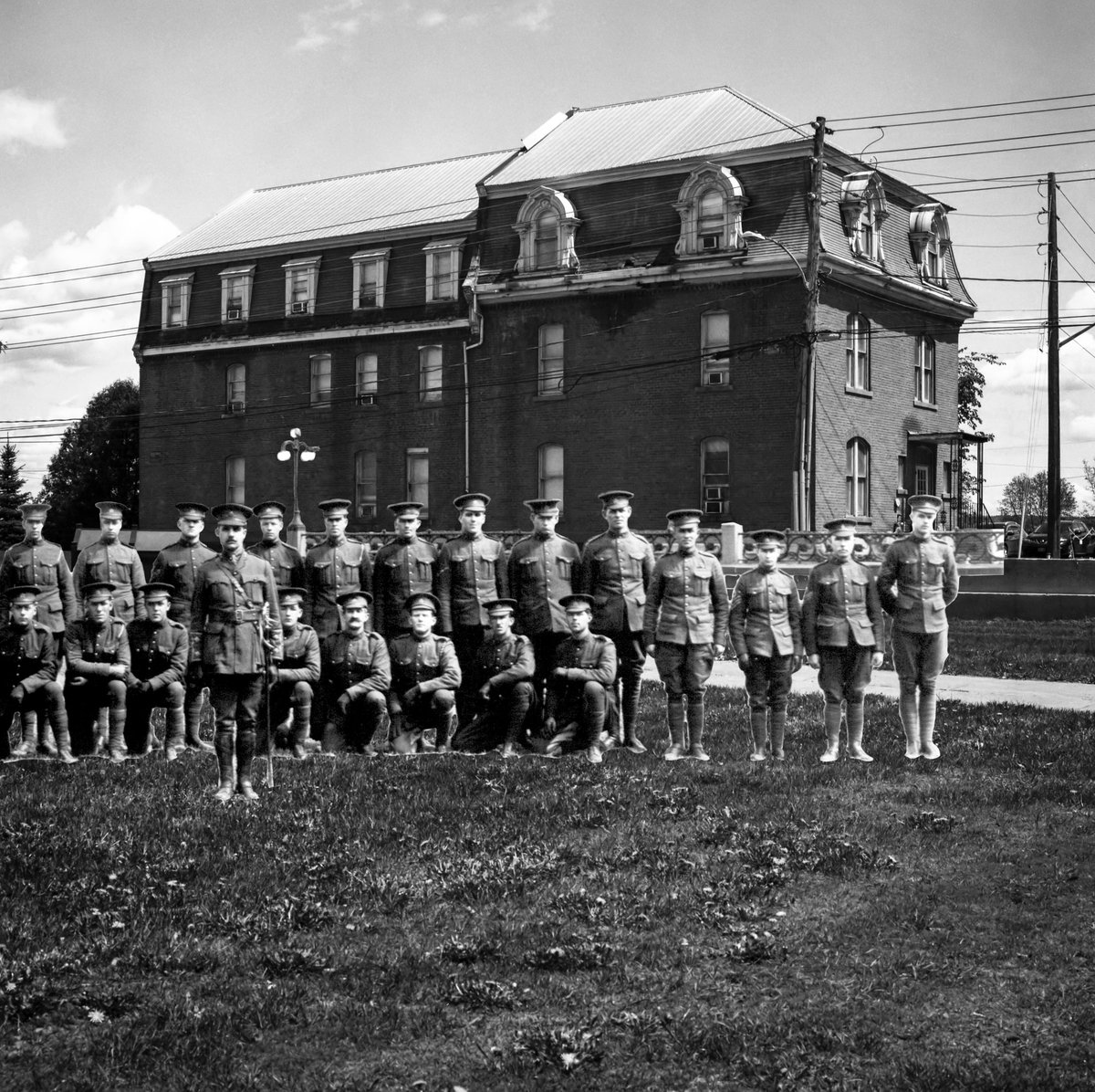 Jeandron's tweet photo. A recent photo of Officers' Square with historic Lemont House (1880) & cropped section of a pano of Officers & Men of the Headquarters, #1 Section, Divisional Ammo Column superimposed, from a 1915 pic prior to their departure to Europe for WW1. Lest we forget. #SaveOfficersSquare https://t.co/eY7su06UMQ