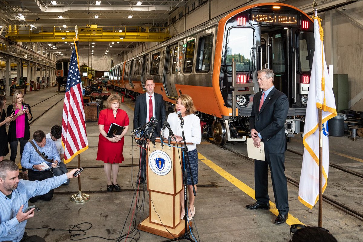Lieutenant Governor Polito at a podium in front of an Orange Line train at Wellington Station