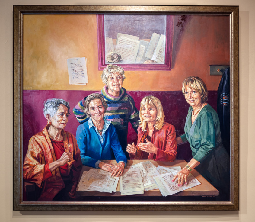 A recent painting, ordered by the University of Amsterdam, portraying 5 female professors wearing casual gear, and sitting or standing around a table with papers.