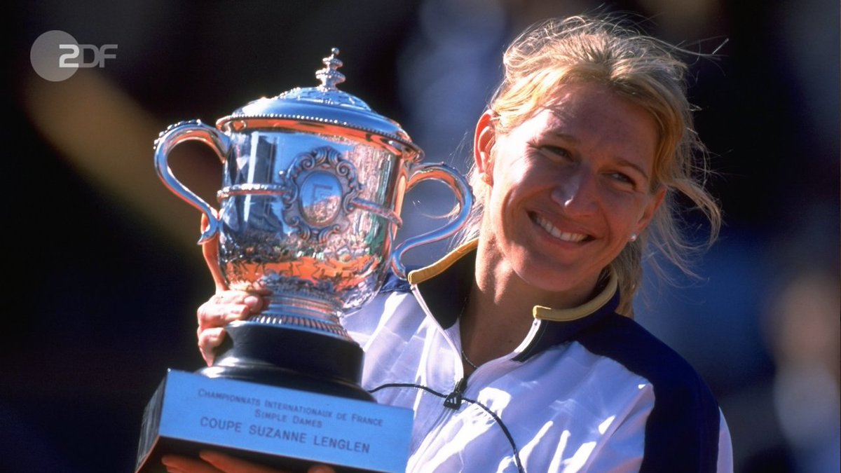 "ZDF-History: Steffi Graf - ein deutscher Weltstar": Steffi Graf steht strahlend mit einem Pokal in de Hand auf dem Platz und hält den Pokal hoch. Sonntag, 23.06.19 um 19:30 Uhr auf ZDFinfo.