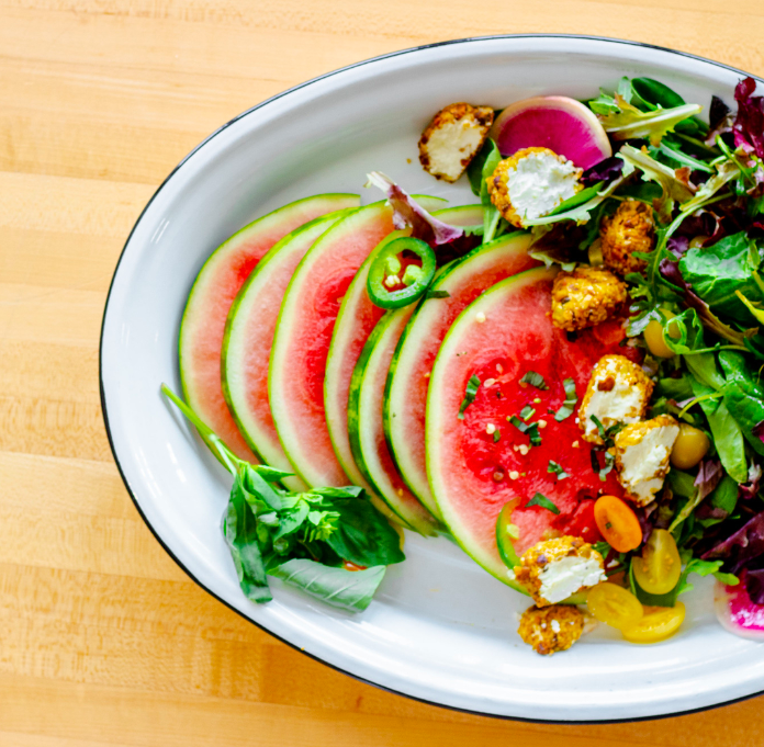 Two words: Watermelon Carpaccio. This seasonal salad features thinly sliced fresh watermelon, heirloom cherry tomatoes, and pistachio-rolled chèvre slices alongside baby greens, drizzled with watermelon, grilled poblano and white-balsamic vinaigrette.  

📸 Emily Winters