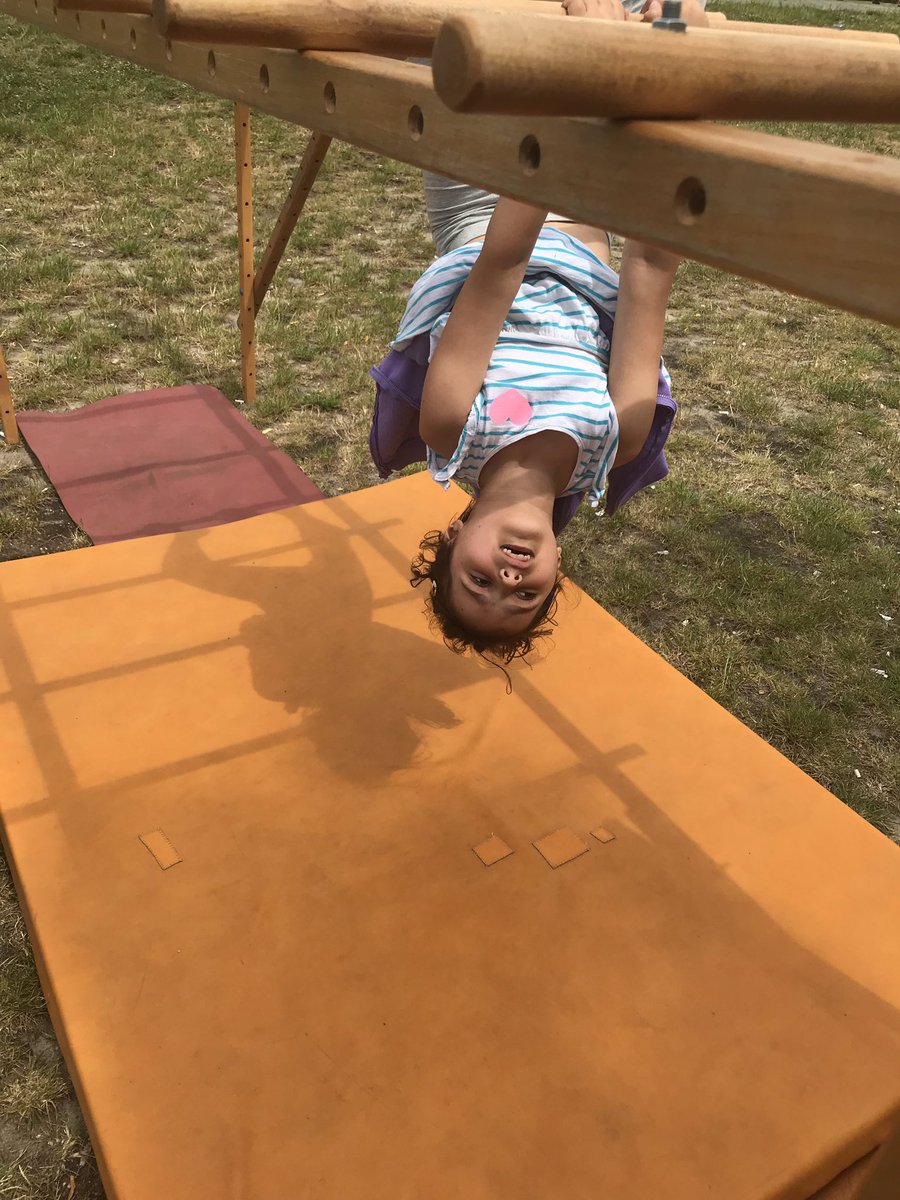 Girl hanging upside down from monkey bars. 