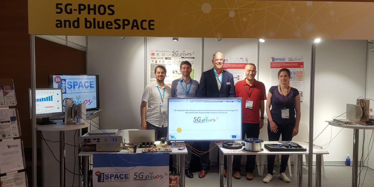 The  <a href="/5GPHOS_social/">5GPHOS</a> team posing at the joint booth with  <a href="/blueSPACE_5G/">blueSPACE</a>,  where a live FiWi A-RoF 60G transmission of a 5G NR waveform is being  succesfully demonstrated during <a href="/EuCNC/">2026 EuCNC & 6G Summit</a> !!  Still one day to visit our  booth and learn more