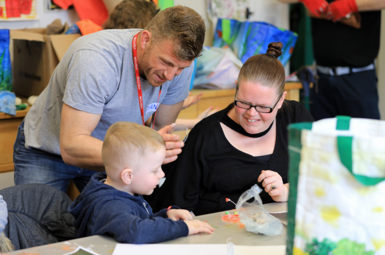 A man, woman and child doing arts and crafts.