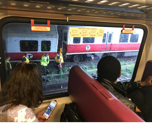Commuters watch crews work on the MBTA tracks.