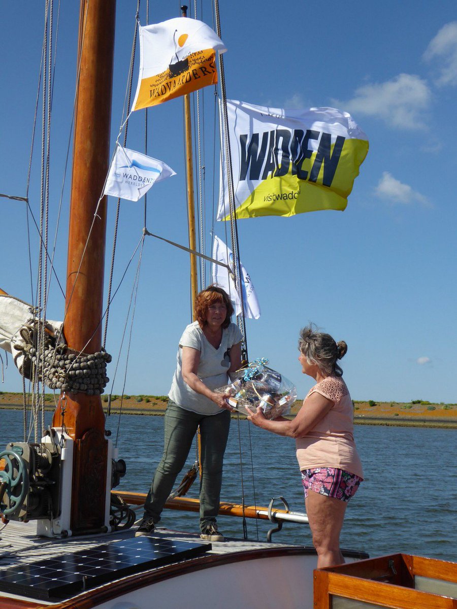 In haven Den Oever vanuit <a href="/uiteigenstreek/">Uit Eigen Streek</a> gechenkpakket met streekproducten uit de Kop van Noord-Holland @waddendelicatessen overhandigd aan Ciska en Frans van Geer van De Strinda. Zij zijn met elf Wadvaarders onderweg voor een estafette in kader 10 jaar Werelderfgoed Waddenzee.