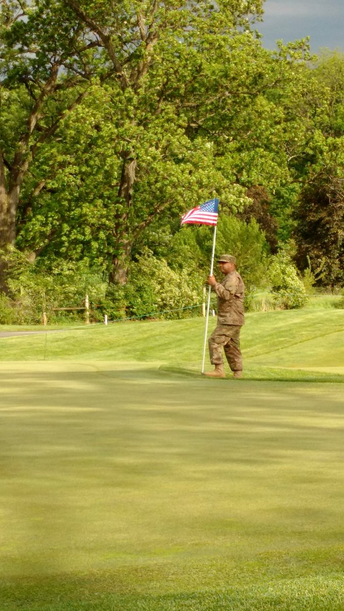 NIUAthletics's tweet photo. U.S. Army Specialist Lorenzo Amaro tends the flag on the 18th green during #SalutetoServiceDay at #NCAAGolf. https://t.co/rk2Bafwyfw