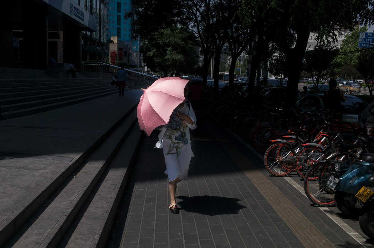 instantmatch's tweet image. A woman protects from the sun in Beijing on May 26, 2017. @MoodysInvSvc slashed China's credit rating on May 24. 
@freddufour_afp @AFPphoto