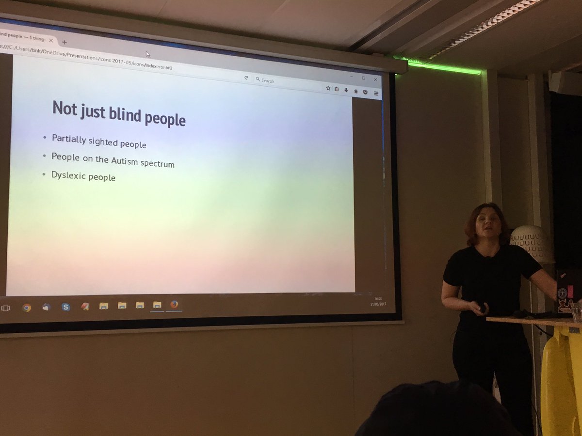 Leonie Watson stood on a podium, screen behind says "Not just blind people. Partially sighted people. People on the Autism spectrum. Dyslexic people"