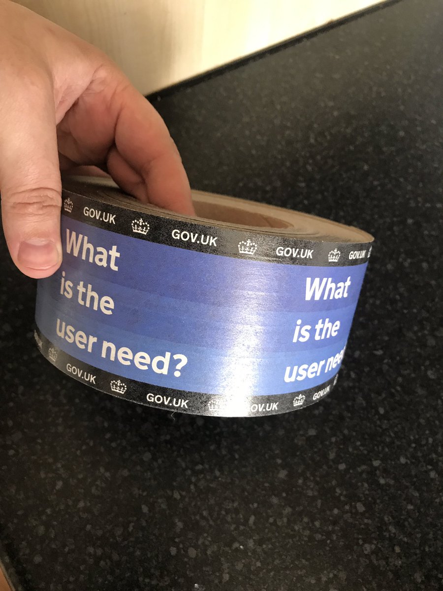 A hand holding a roll of tape, with 'what is the user need?' printed on it