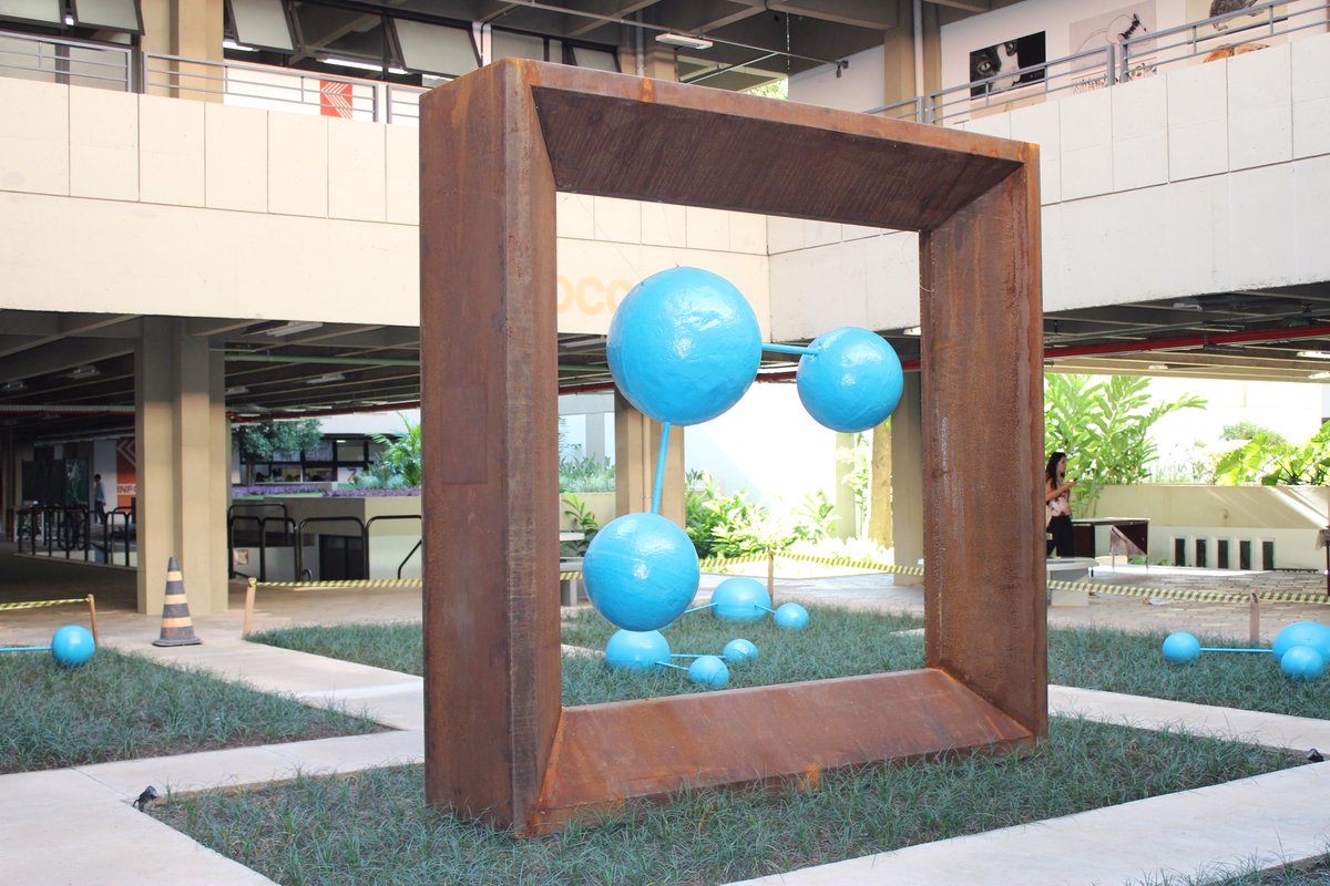 Representação tridimensional de molécula de água, na cor azul, emoldurada por estrutura de aço.