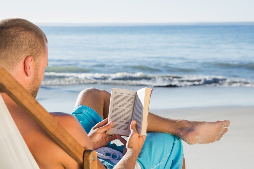 A book to read on holidays. Чтение на пляже. Читать на пляже. Чтение на море. Человек на пляже читает.