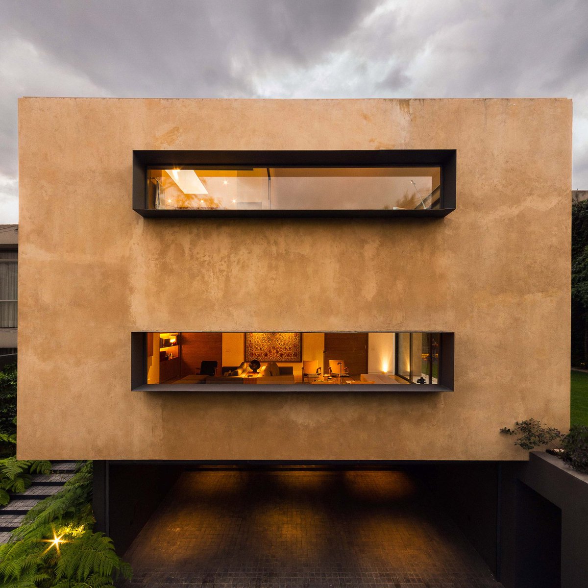 dezeen's tweet image. Andres Stebelski elevates clay-covered house above parking spot near Mexico City woods: on.dezeen.com/a28xE5