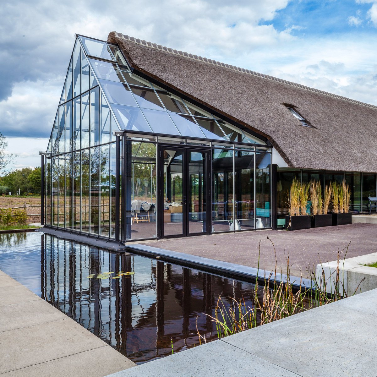 dezeen's tweet image. Maas Architecten has merged a thatched cottage with a glass greenhouse: on.dezeen.com/BQGBAG