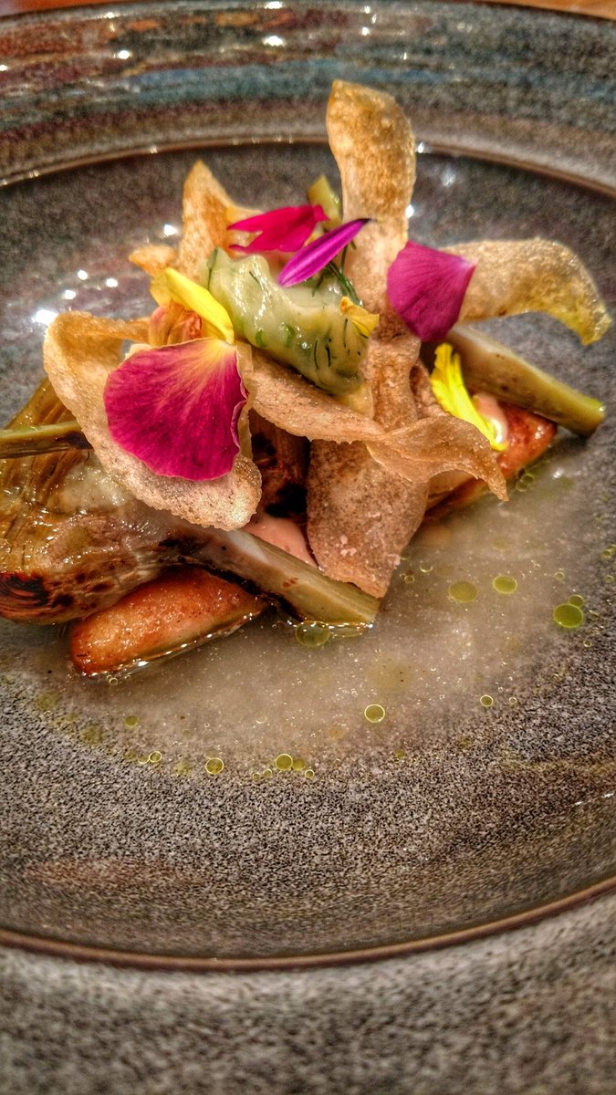 Pan-seared monkfish with roasted artichokes, preserved lemons, malted bone broth, soft herb butter, crisp potato and garnished with flowers