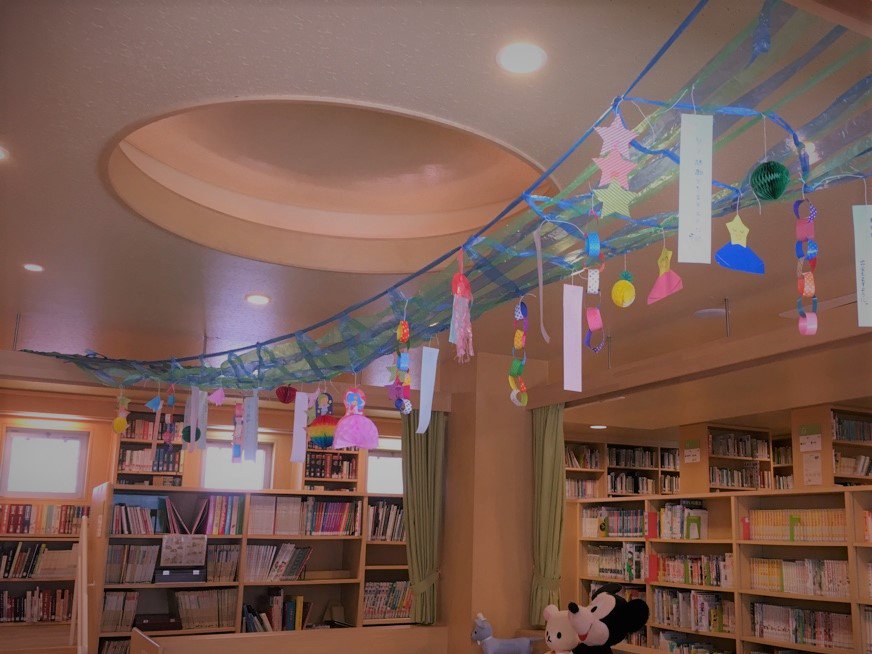 名古屋文化学園保育専門学校 校長デスク 子ども図書室の天井を飾っているのは2部1年生の製作した七夕飾り です 願いを書いた短冊 輪飾りやお星さまの飾りをスズランテープの天の川にこよりで結び付けてあります 願い事は みんながげんきですごせますよう