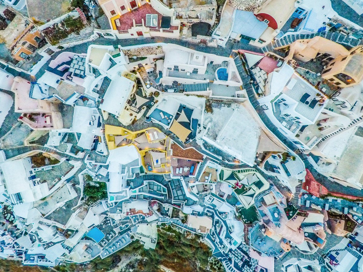 A jigsaw puzzle of cliffside architecture coalesces into a dizzying, Dr. Seuss like tableau from above. #Greece #drone