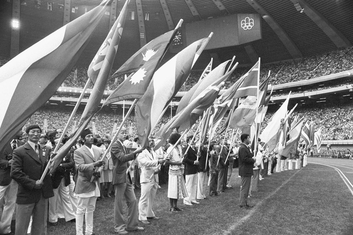 Black and photo of flag bearers standing in a row in the opening ceremonies of the Montreal Olympics Games