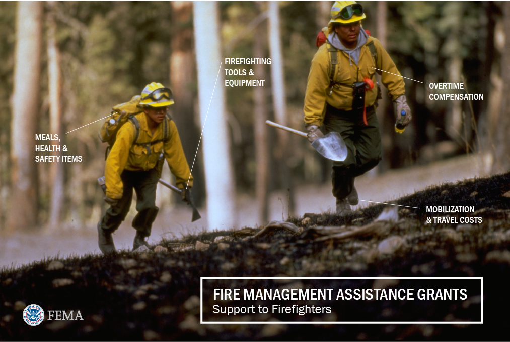 Two New Mexico firefighters walk up a hill to continue battling smoldering forest fires. Labels point to the types of costs Fire Management Assistance Grants can cover to support firefighters. Text overlay reads: "Fire Management Assistance Grants, Support to firefighters. • Firefighting tools and equipment • Overtime compensation • Mobilization and travel costs • Meals, health and safety items."