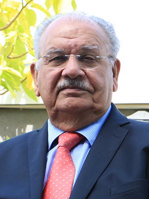 Naresh Chandra outdoors wearing a dark suit and glasses looking directly at camera in 2017.