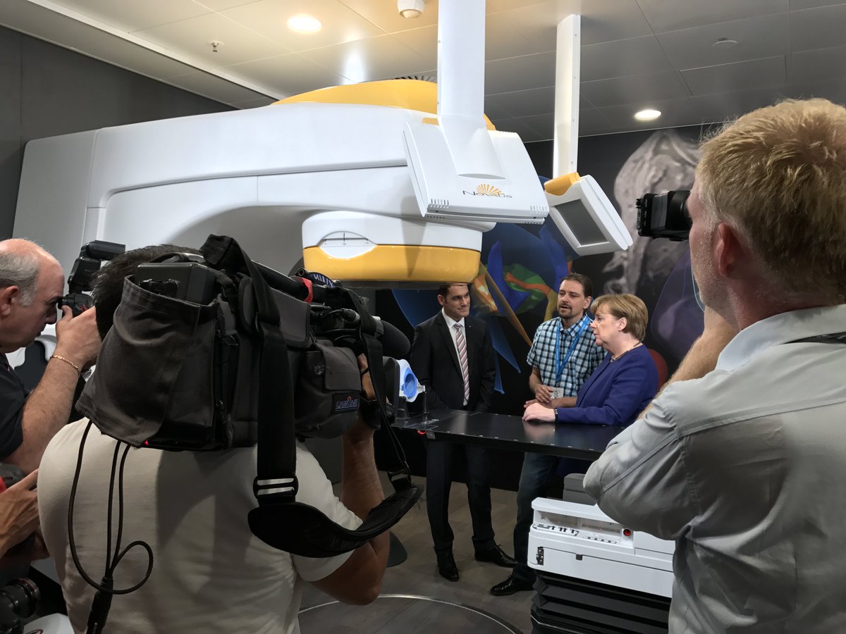 Brainlab's tweet photo. Stefan Vilsmeier discussing comprehensive #radiosurgery and #ExacTrac patient positioning &amp; monitoring w/ Chancellor Angela #Merkel. https://t.co/bS9iaGCDeY