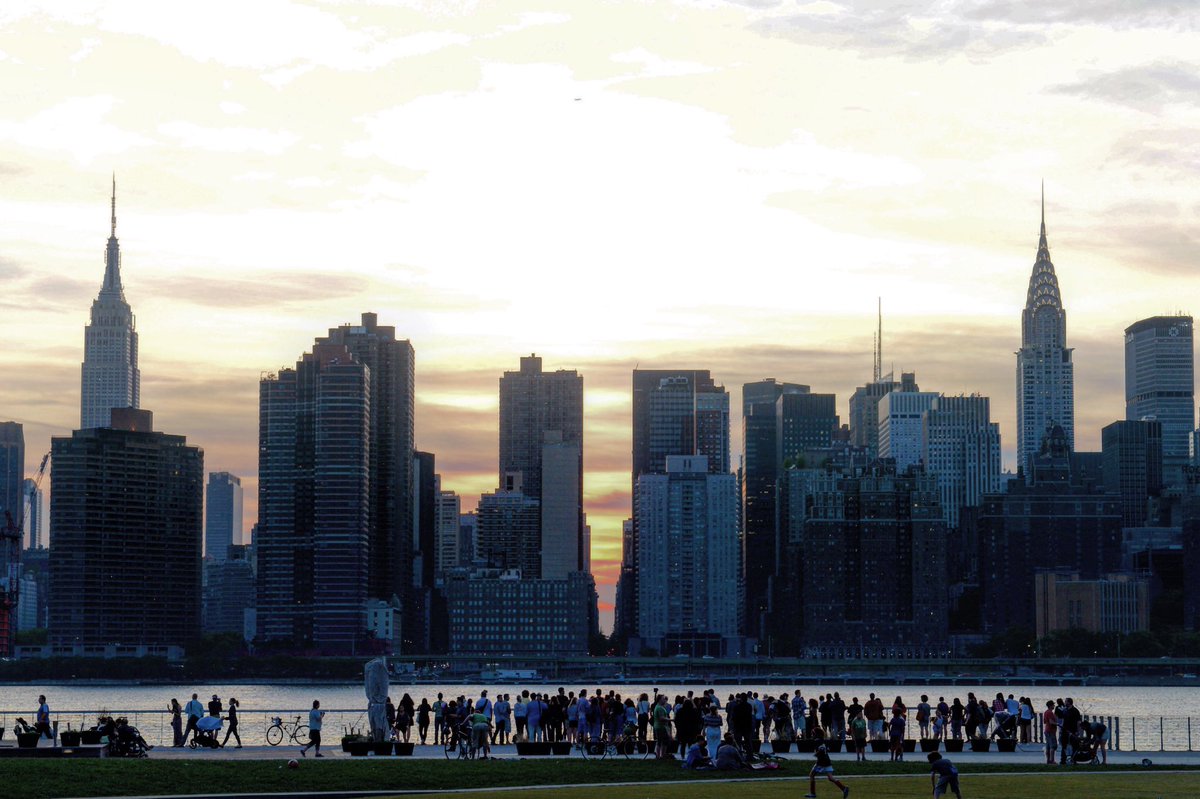 Parkgoers line up along the Hunter's Point South Park waterfront to look at the sun setting on the Manhattan street grid.