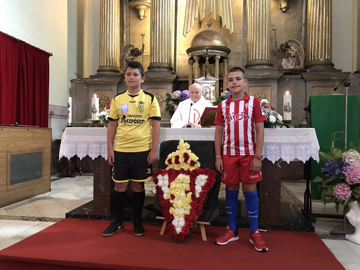 Los primeros actos comienzan en #VegadeoRojiblanco y los niños portan un escudo del Sporting en la misa por los peñistas fallecidos.
