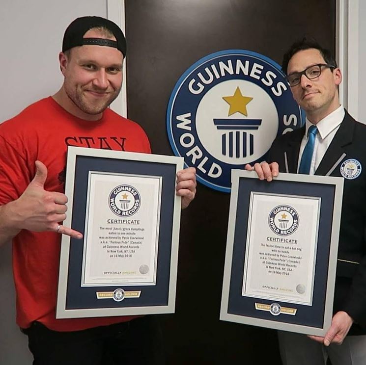 Peter Czerwinski standing with an official Guinness World Record judge with two Guinness World Records certificates